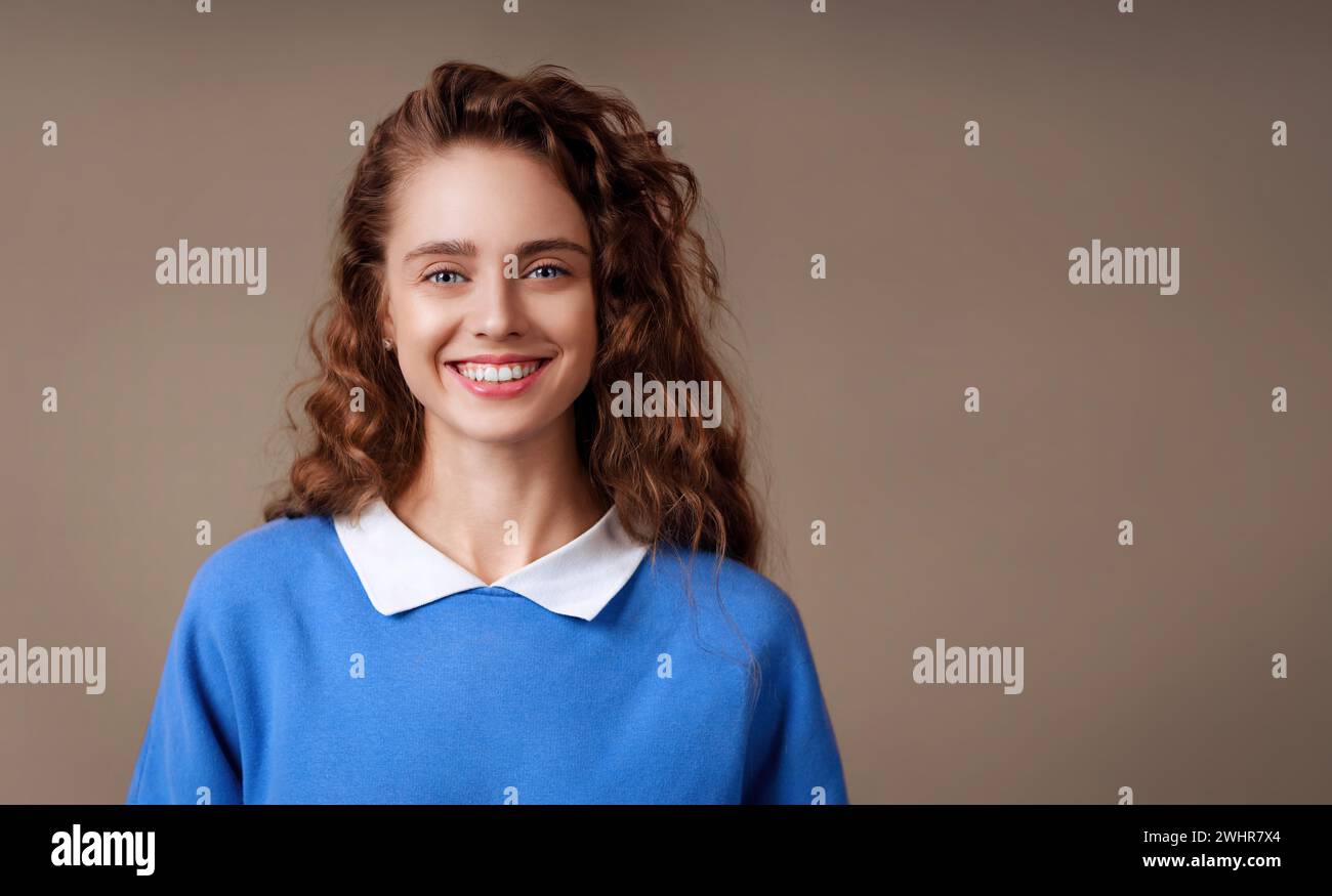 Lächelnde junge positive Frau Porträt, die mit einem breiten Lächeln in die Kamera schaut. Positiv denkendes Mädchen Stockfoto