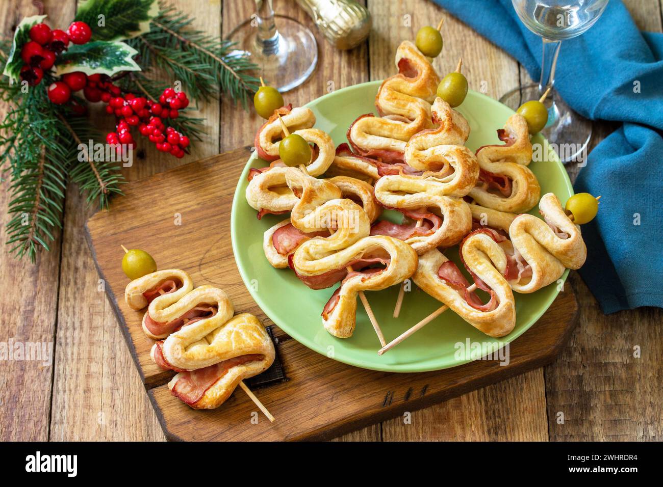 Essen zu Weihnachten und Neujahr. Weihnachts-Snack Blätterteig Weihnachtsbaum mit Oliven und Speck auf einem Holztisch. Stockfoto