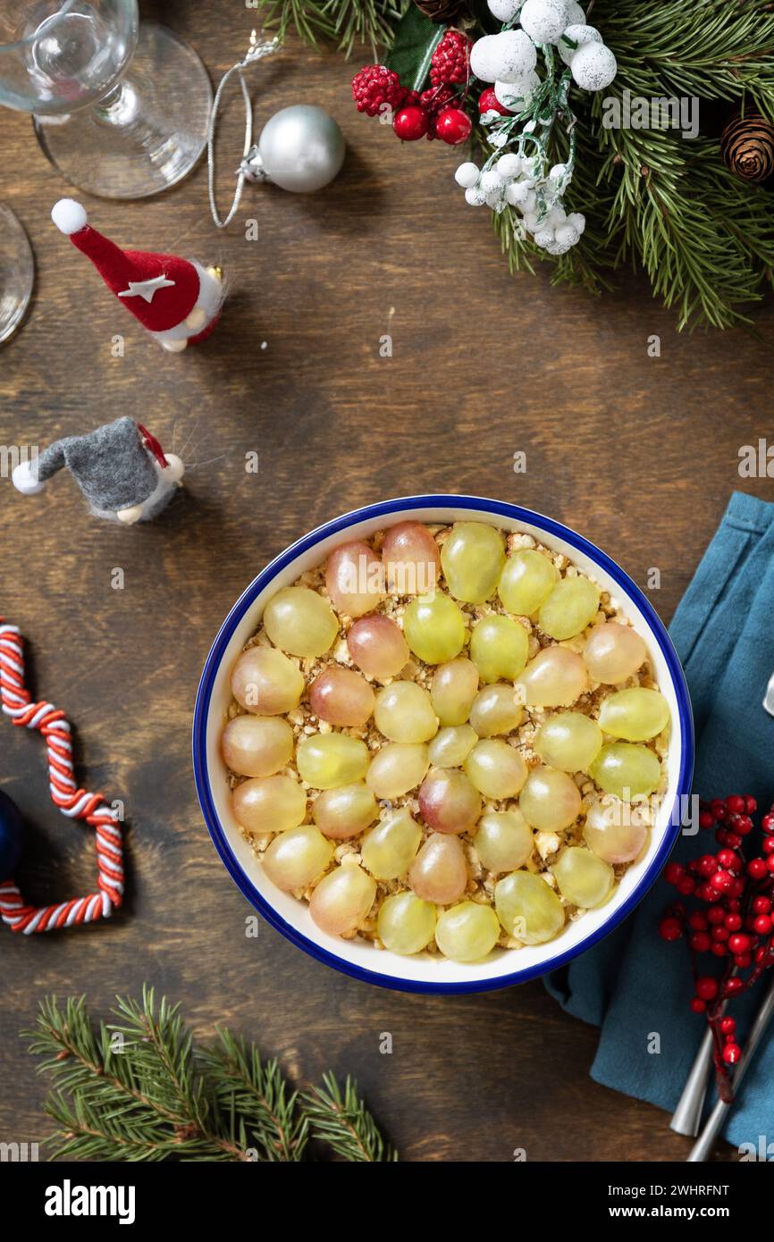 Winterweihnachtsalat. Köstlicher Salat mit Huhn, Käse, Walnüssen und Trauben auf einem festlichen Tisch. Blick von oben. Stockfoto