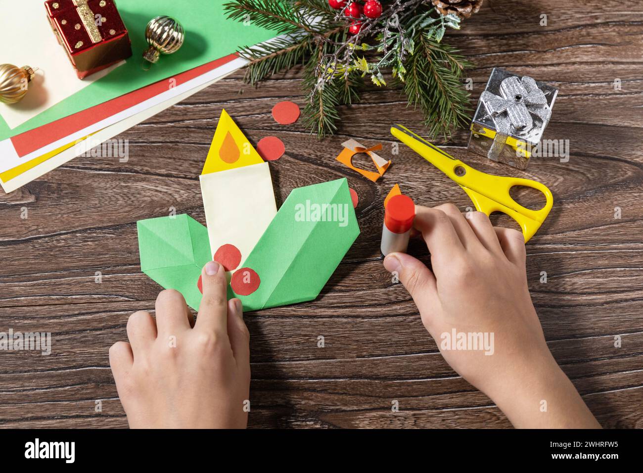 Anweisungsschritt 12. Weihnachtsgrußkarte Geschenk Origami Kerze auf Holztisch. Kinderkunstprojekt, handgemacht, Kunsthandwerk für Ki Stockfoto