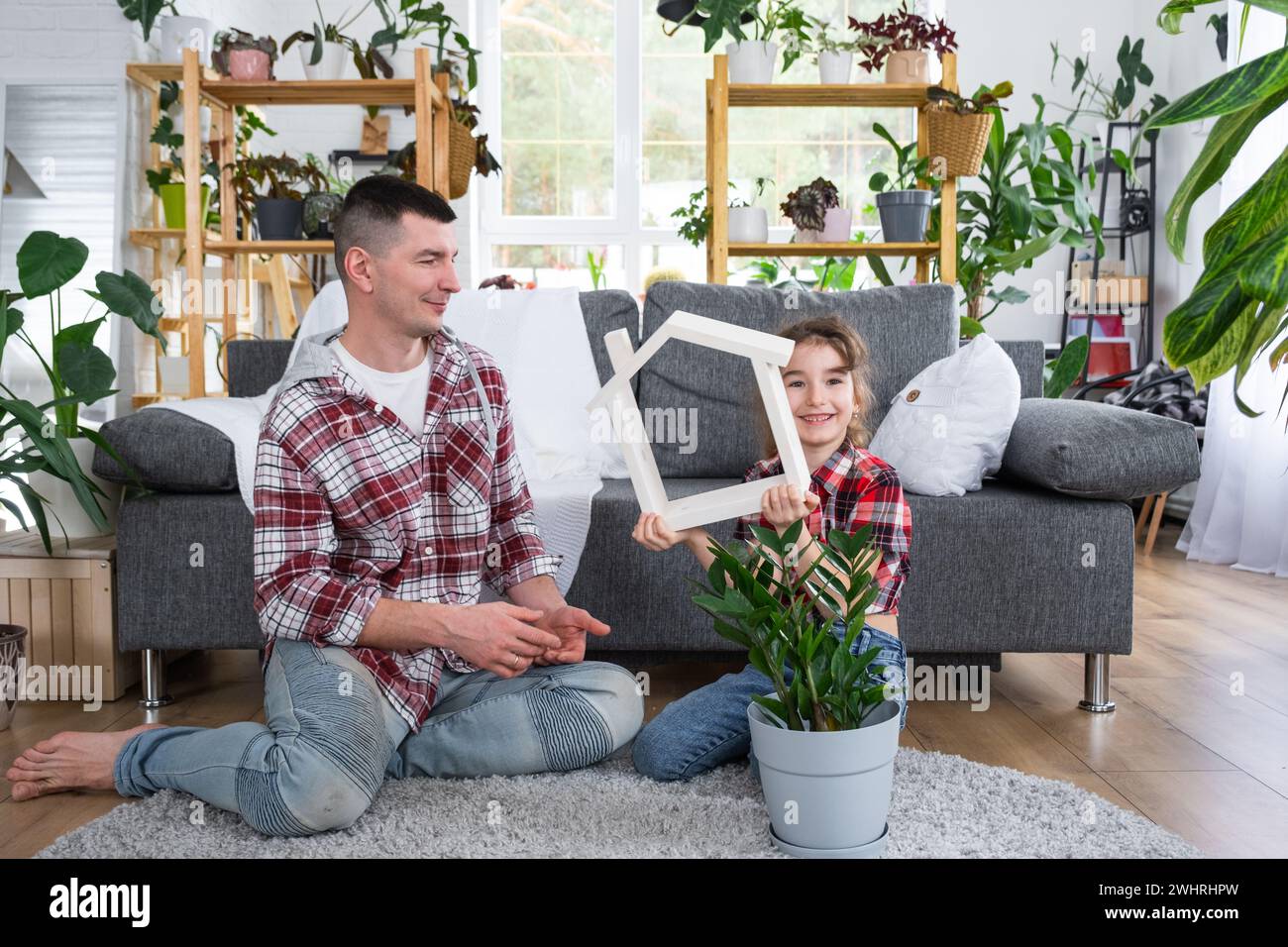 Unvollständige Familie Vater und Tochter genießen ein neues Zuhause, sitzen auf dem Sofa. Hypothek, Versicherung und Schutz, Kauf und Umzug Stockfoto
