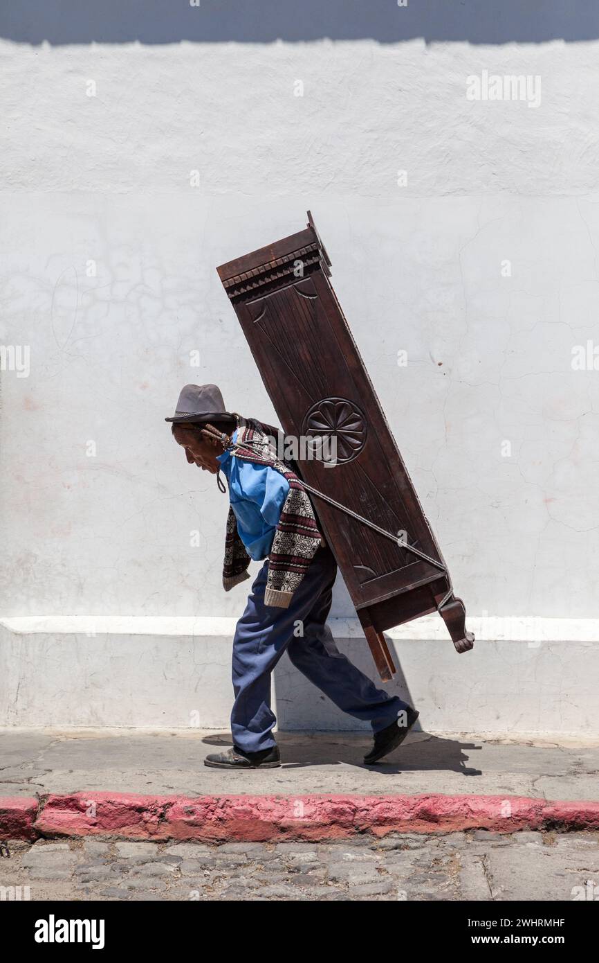 Antigua, Guatemala. Arbeiter trägt Möbel auf dem Rücken, Seil um die Stirn. Stockfoto