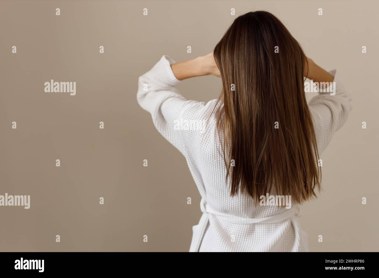 Junge Frau mit gesunden langen glatten Haaren im weißen Bademantel, Rückansicht. Hygiene, Frische, Reinigung nach dem Duschen. Wirkung von Co Stockfoto