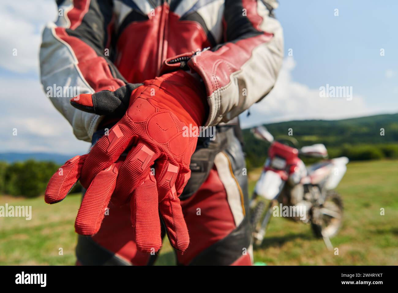 Ein professioneller Motocross-Fahrer, der seine Handschuhe trägt und sich auf eine professionelle Motocross-Fahrt vorbereitet Stockfoto