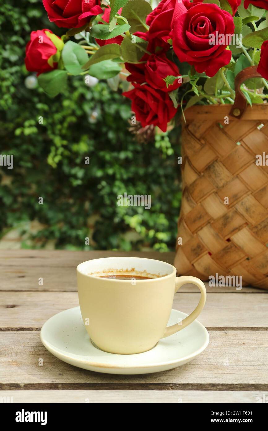 Eine Tasse Kaffee mit einem Korb Rosen im Hintergrund Stockfoto