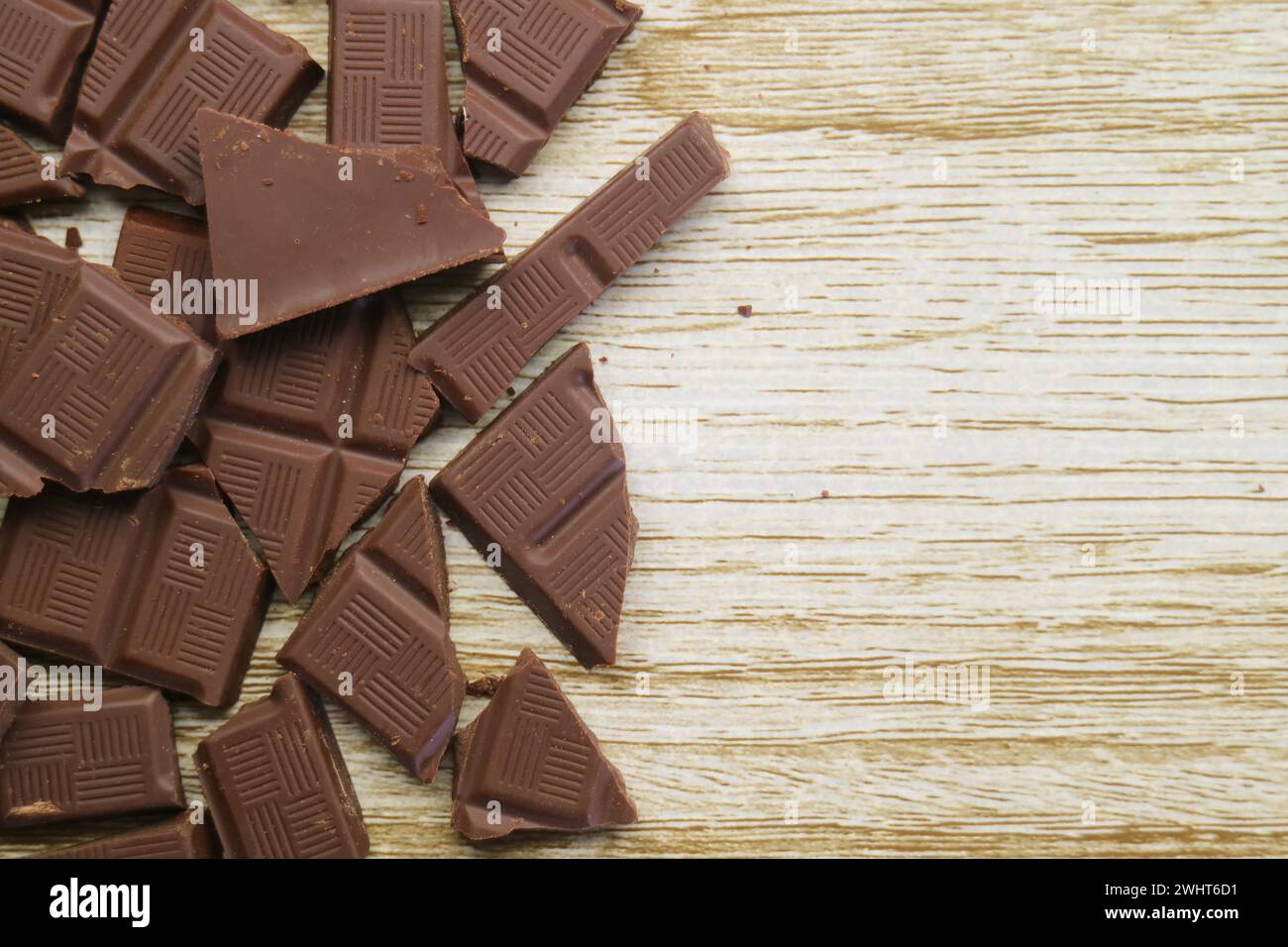 Ein Haufen zerbrochener dunkler Schokoladenstücke auf Holzhintergrund Stockfoto