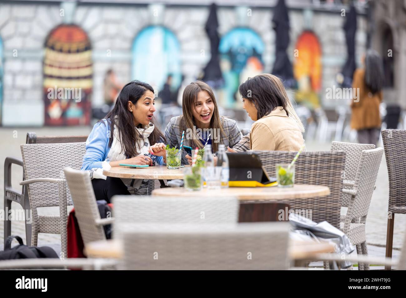 Vielseitige Geschäftsfrauen genießen Cocktails und teilen Überraschungen in European City Stockfoto