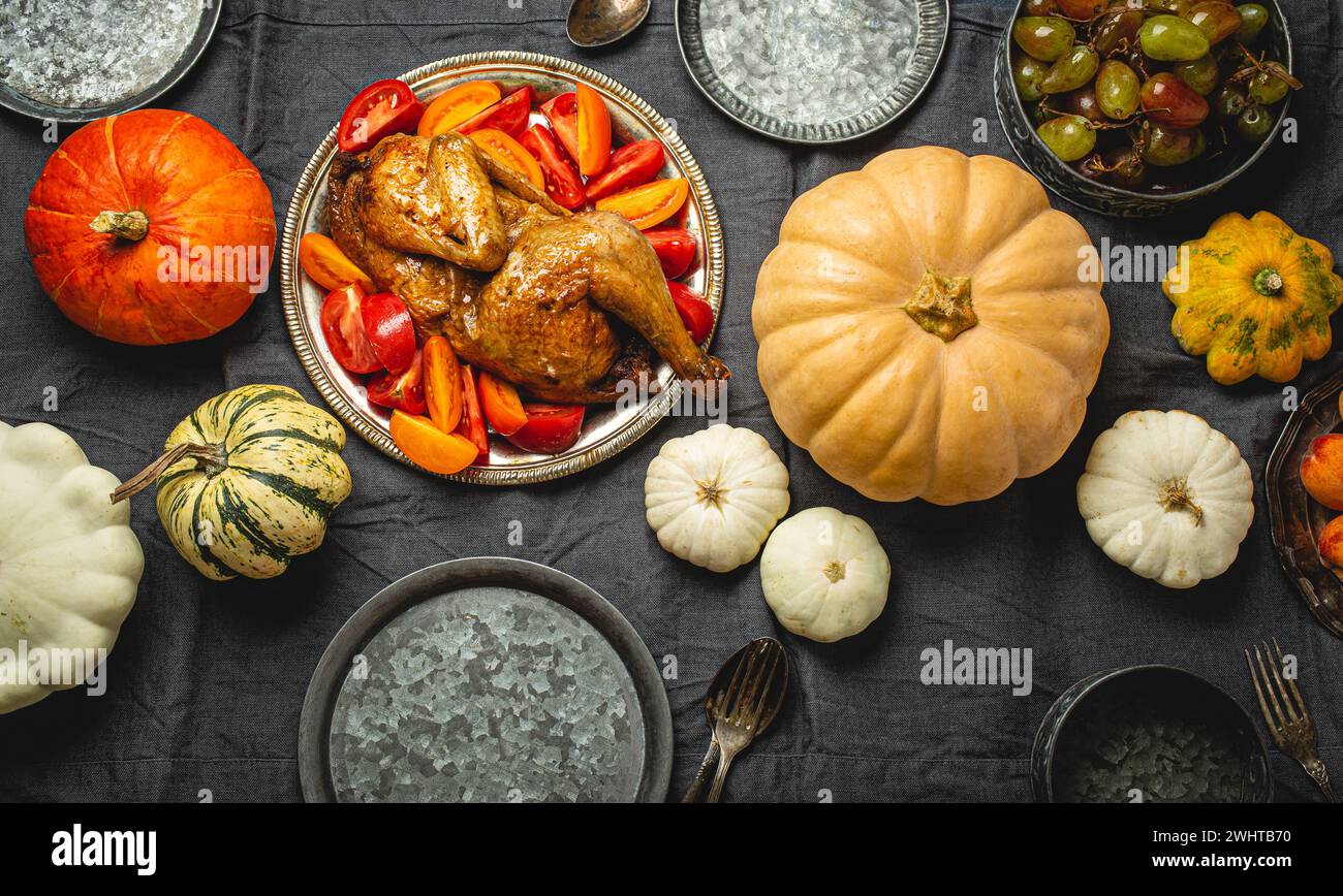 Festliche Tischkomposition zu Thanksgiving mit gebratenem truthahn, Kürbissen, Gemüsesalat, Obst, Orangengetränk. Thanksgiving-Cele Stockfoto