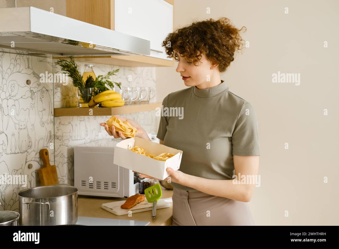 Junge Frau, die Pappardelle-Pasta in den Händen hält, über den Topf mit kochendem Wasser Stockfoto