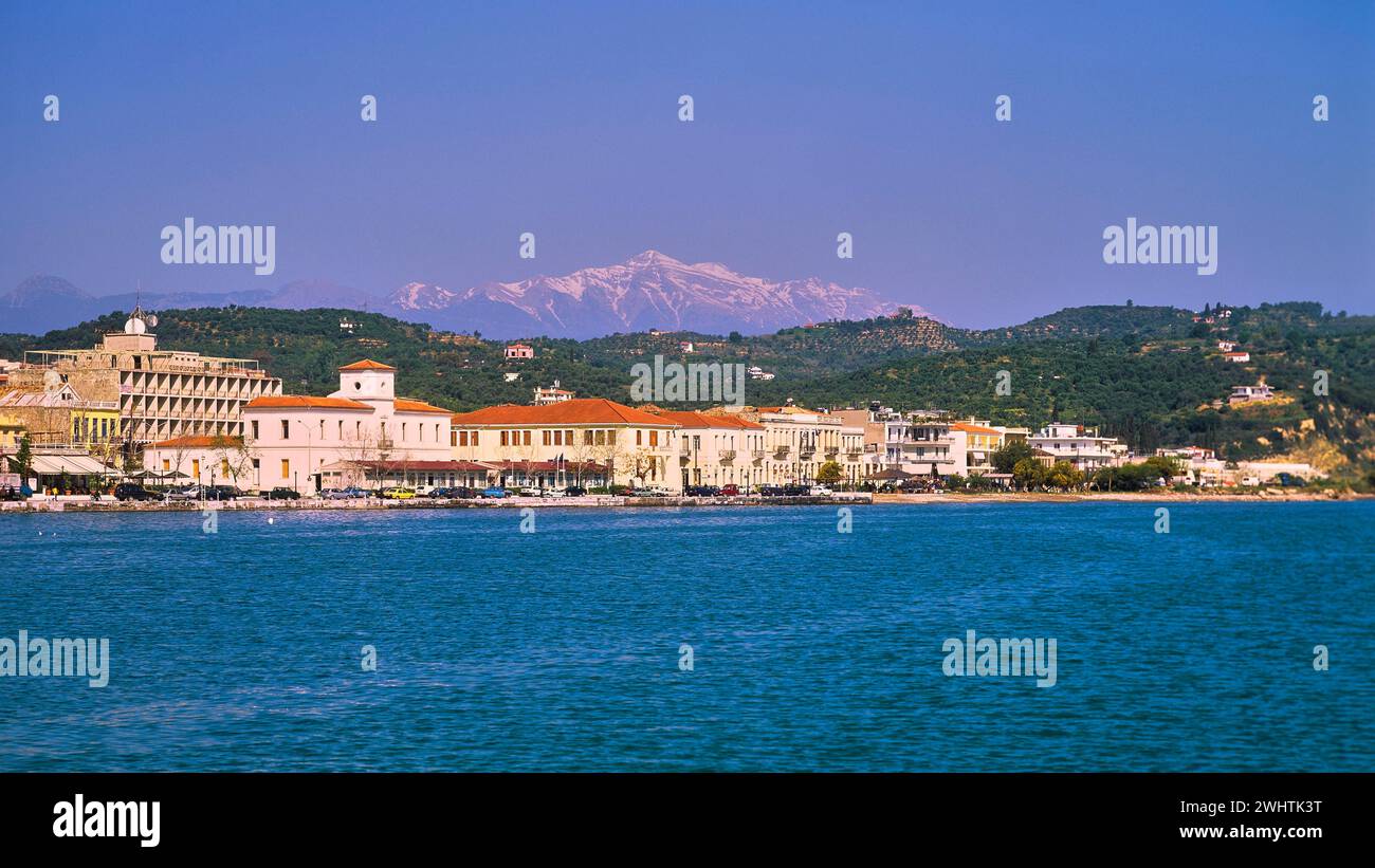 Blick auf die Küstenstadt mit Gebäuden vor einer Bergkulisse unter einem klaren blauen Himmel, schneebedeckten Taygetos Mountains, Taygetos, Gythio, Mani Stockfoto