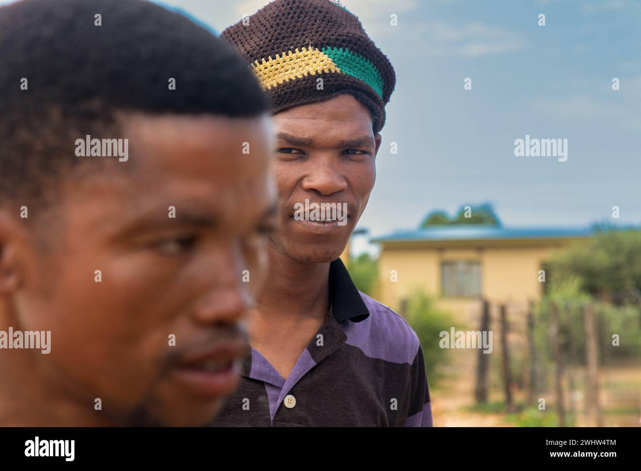 Dorf, Porträt von zwei afrikanischen Männern, die eine Mütze tragen, tagsüber vor dem Haus Stockfoto