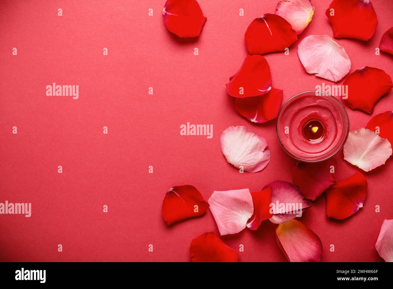 Roter Hintergrund mit Rosenblättern und brennenden Kerzen. Liebes- und Passionskonzept Stockfoto