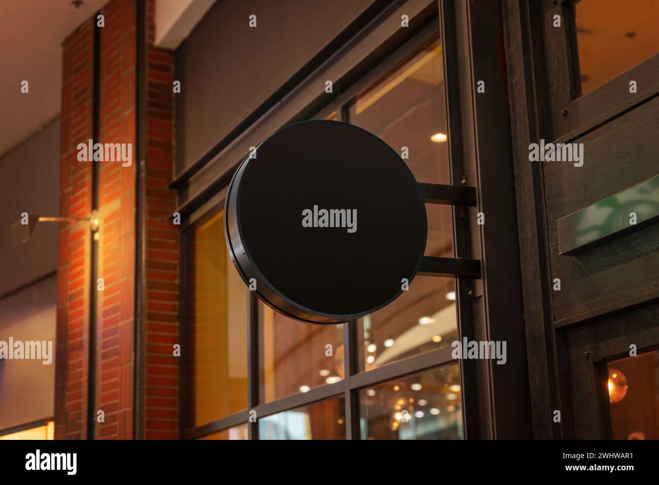 Schwarzes, rundes Logo-Werbezeichen in einem Einkaufszentrum, das ein schlankes und auffälliges Display bietet, um Kunden anzulocken und die Markenpräsenz zu verbessern Stockfoto