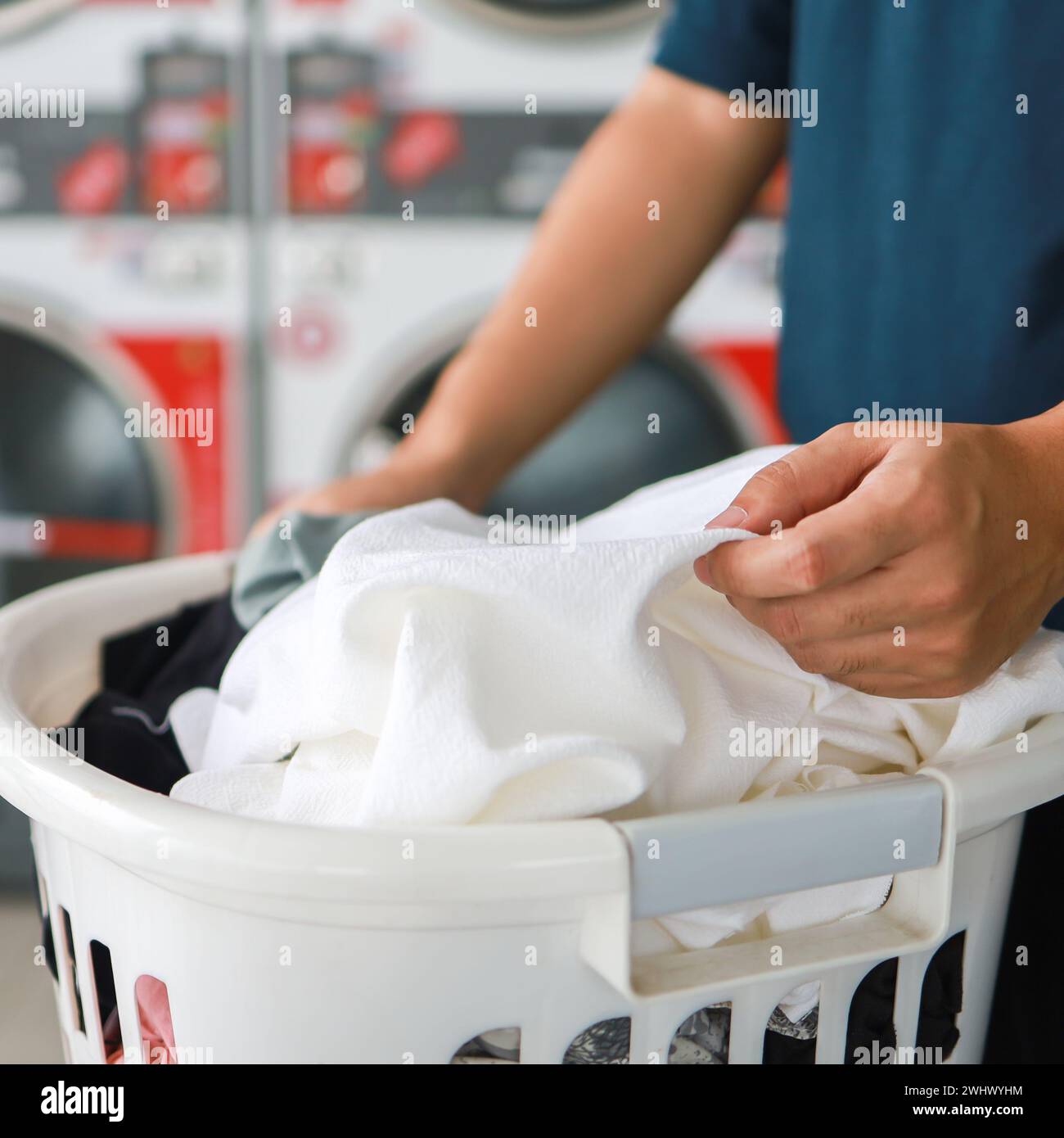 Mann, der einen Waschkorb mit schmutziger Wäsche der Waschmaschine im öffentlichen Geschäft hält. Wäschekleidung Konzept Stockfoto