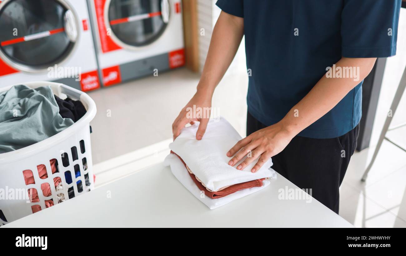 Hausmann mit Korb und schmutziger laundryÂ gewaschener Kleidung im Waschraum. Waschen machineÂ im Wäschereigeschäft Stockfoto