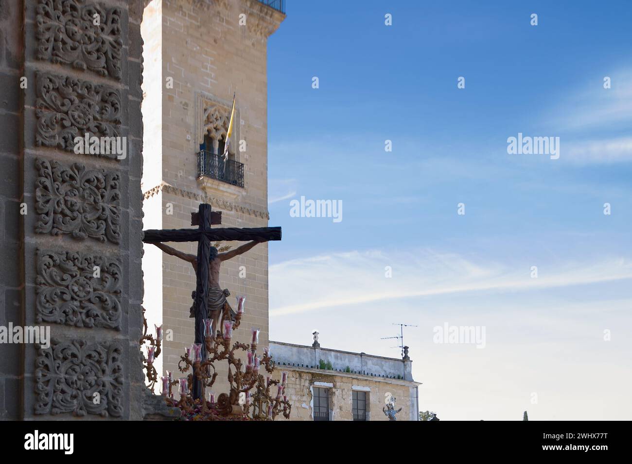 Bild, aufgenommen während der Karwoche in Jerez de la Frontera, Spanien, mit einem kunstvollen Kreuz vor der Kathedrale unter einem klaren blauen Himmel. Stockfoto