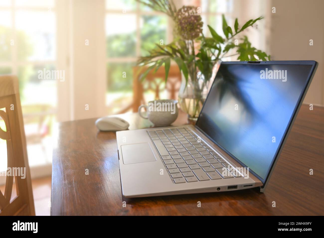 Laptop Computer auf einem Holztisch mit Kaffeetasse und Blumenstrauß im Esszimmer, Home Office Arbeit, Kopierraum, Auswahl Stockfoto