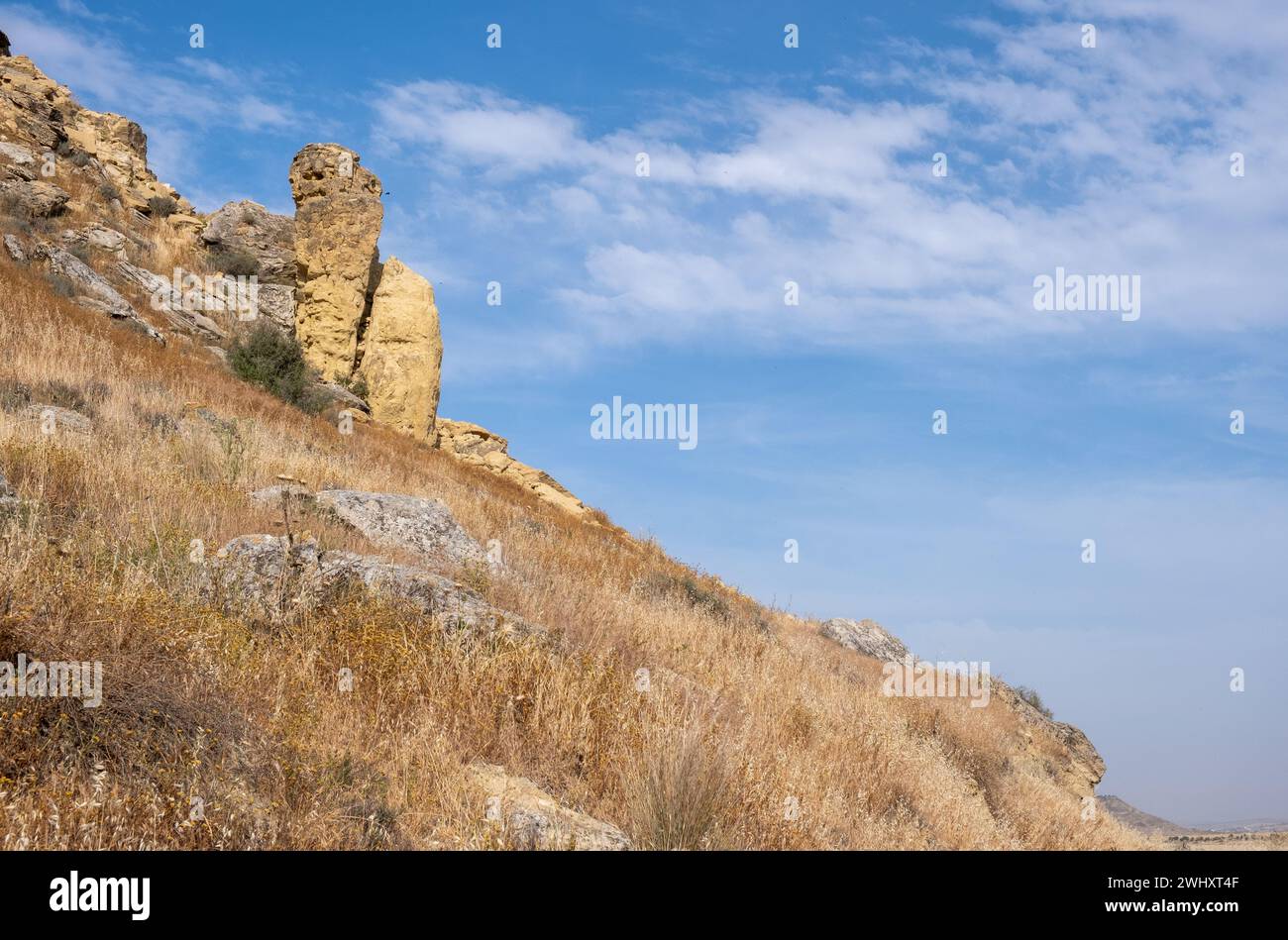 Natürliche Gesteinsbildung am Hang einer trockenen Klippe. Bewölkter blauer Himmel. Outdoor-Abenteuer Stockfoto
