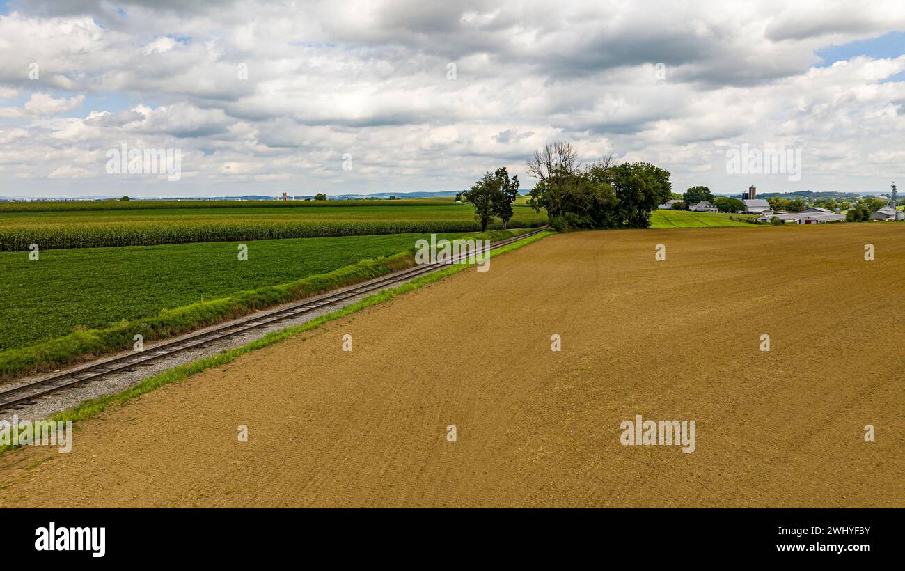 Luftaufnahme des ländlichen Amerikas mit Ackerland und einem Single Rail Road Track, der durch das Land führt Stockfoto