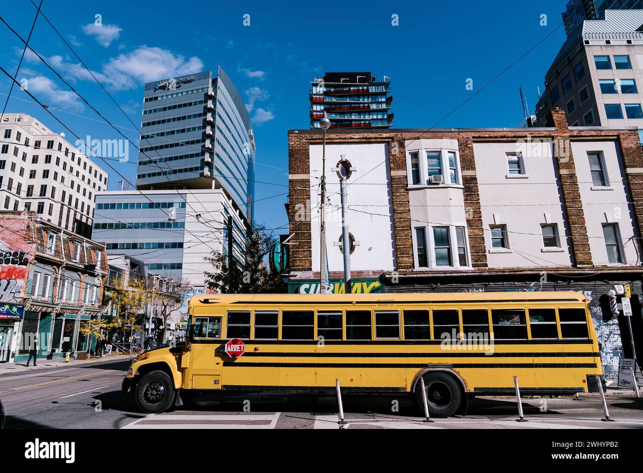 Toronto, Kanada - 28. Oktober 2023: Eine pulsierende Stadtstraße mit einem gelben Schulbus im Vordergrund, der ältere Brick kontrastiert Stockfoto