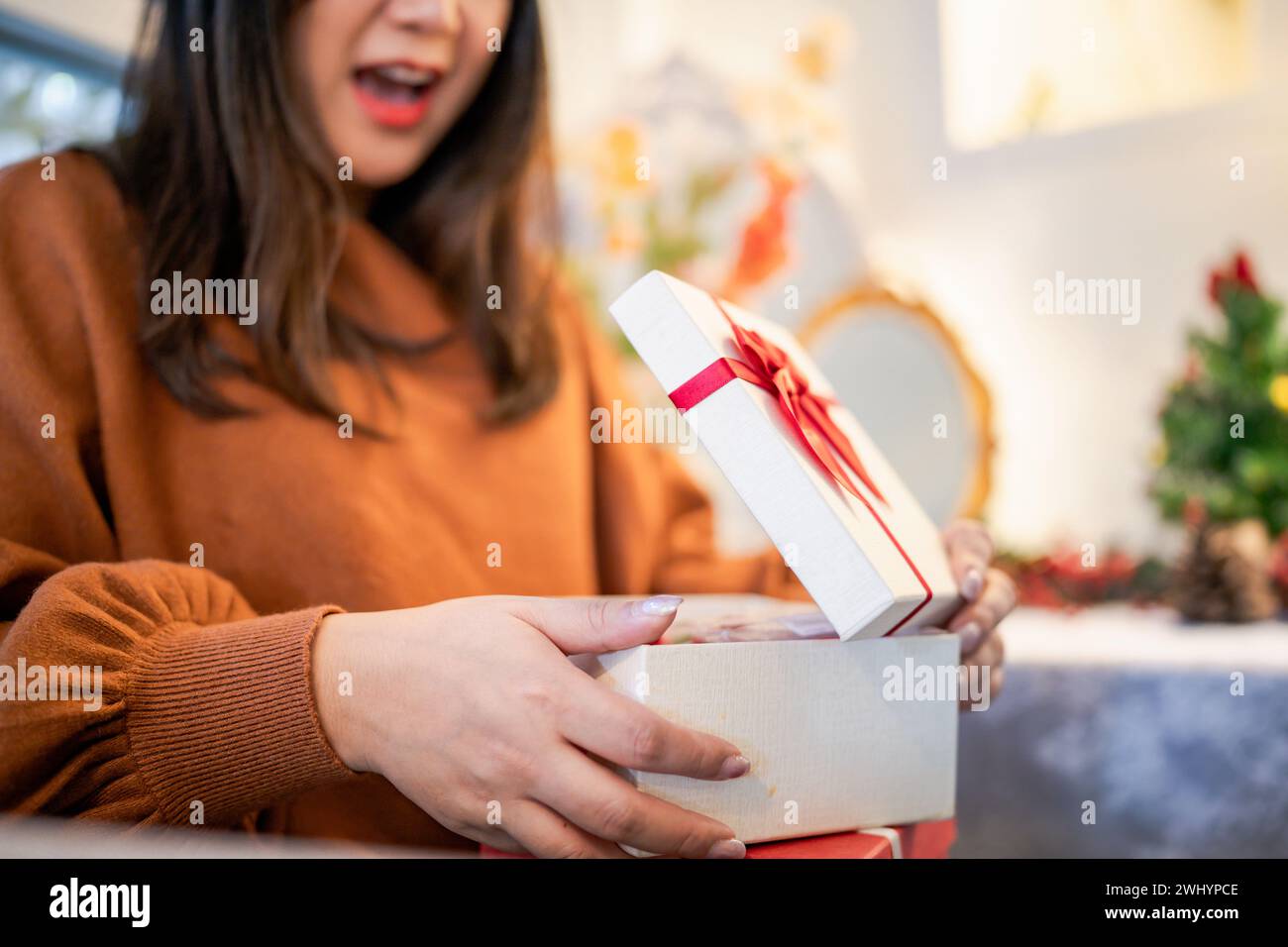 Glückliche asiatische Frau öffnet Weihnachtsbox und Überraschungen. Überraschung für Weihnachten im Urlaub Stockfoto