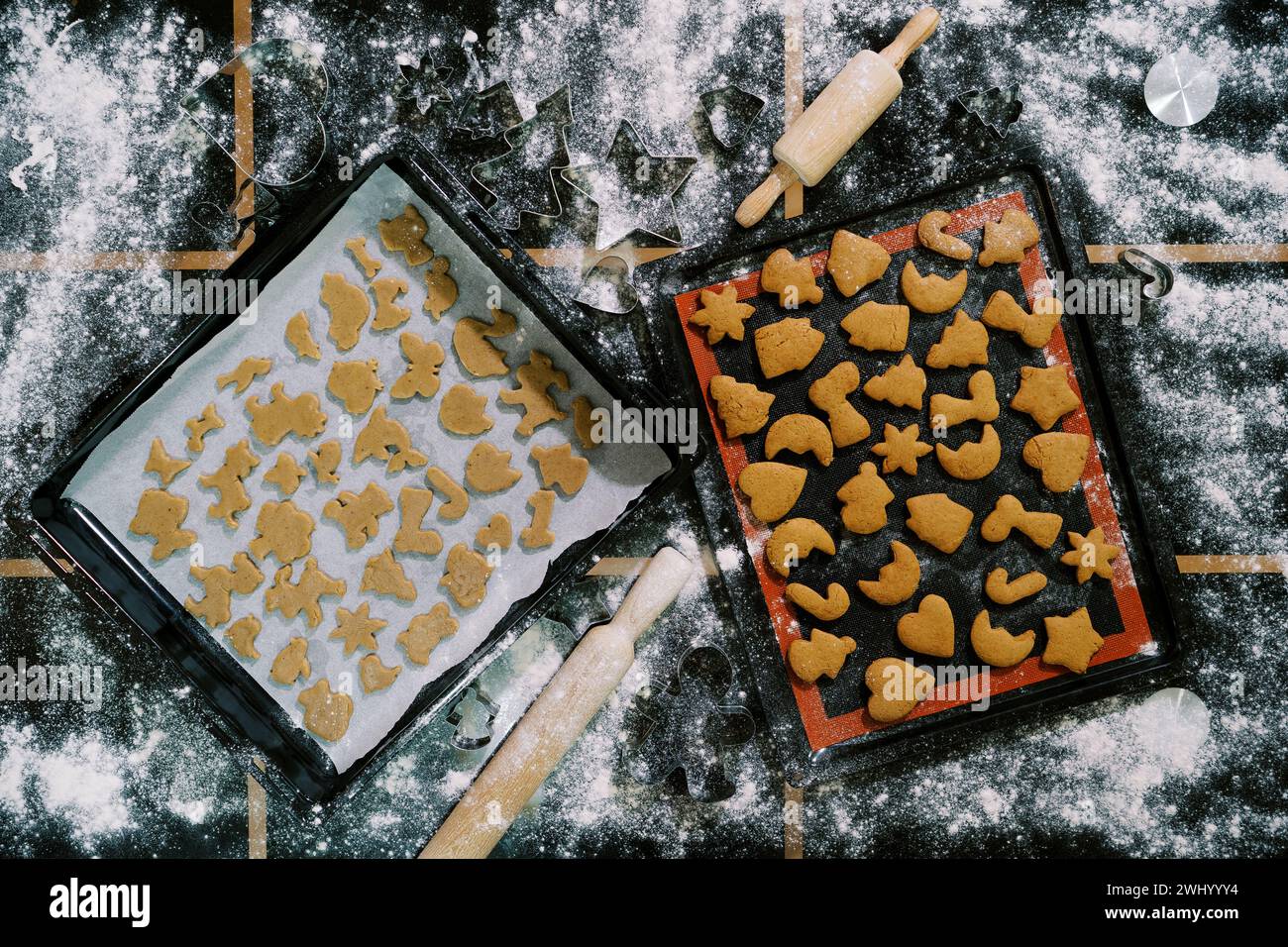 Tabletts mit rohen und gebackenen Keksen stehen auf einem bemehlten Tisch. Draufsicht Stockfoto