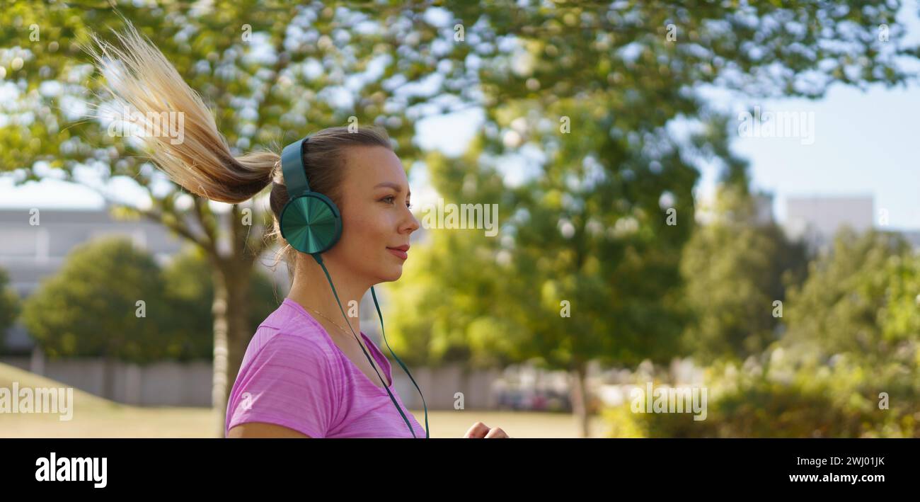 Eine junge Frau, die draußen läuft und Musik hört. Sport nach der Arbeit für eine gute psychische Gesundheit, körperliche Gesundheit, Stressabbau und Stimmung Stockfoto