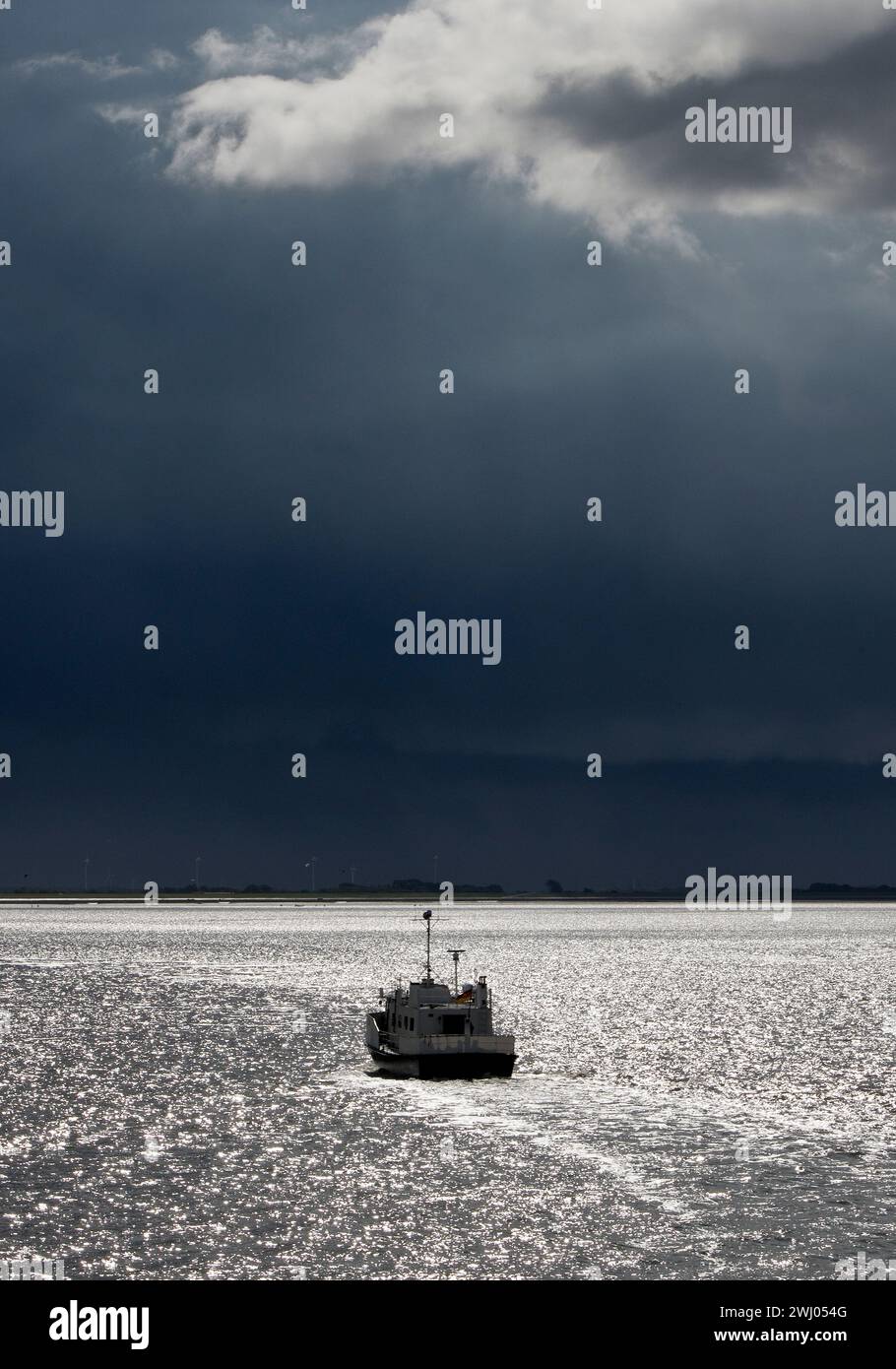 Schiff auf der Nordsee hinterleuchtet mit einem dramatischen dunklen Himmel, Ostfriesland, Niedersachsen, Deutschland, Europa Stockfoto
