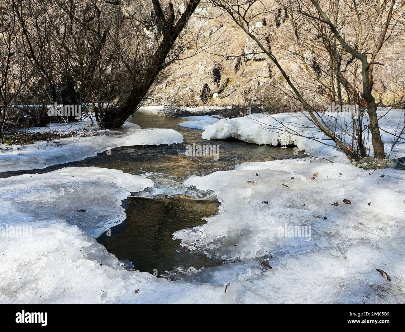 Weißes Eis und Schnee auf gefrorenem Fluss, Wasser fließt darunter, Winterhintergrund. Bäche und Flüsse schmelzen Eis, Frühling. Schneeschmelze, Strömung. Stockfoto