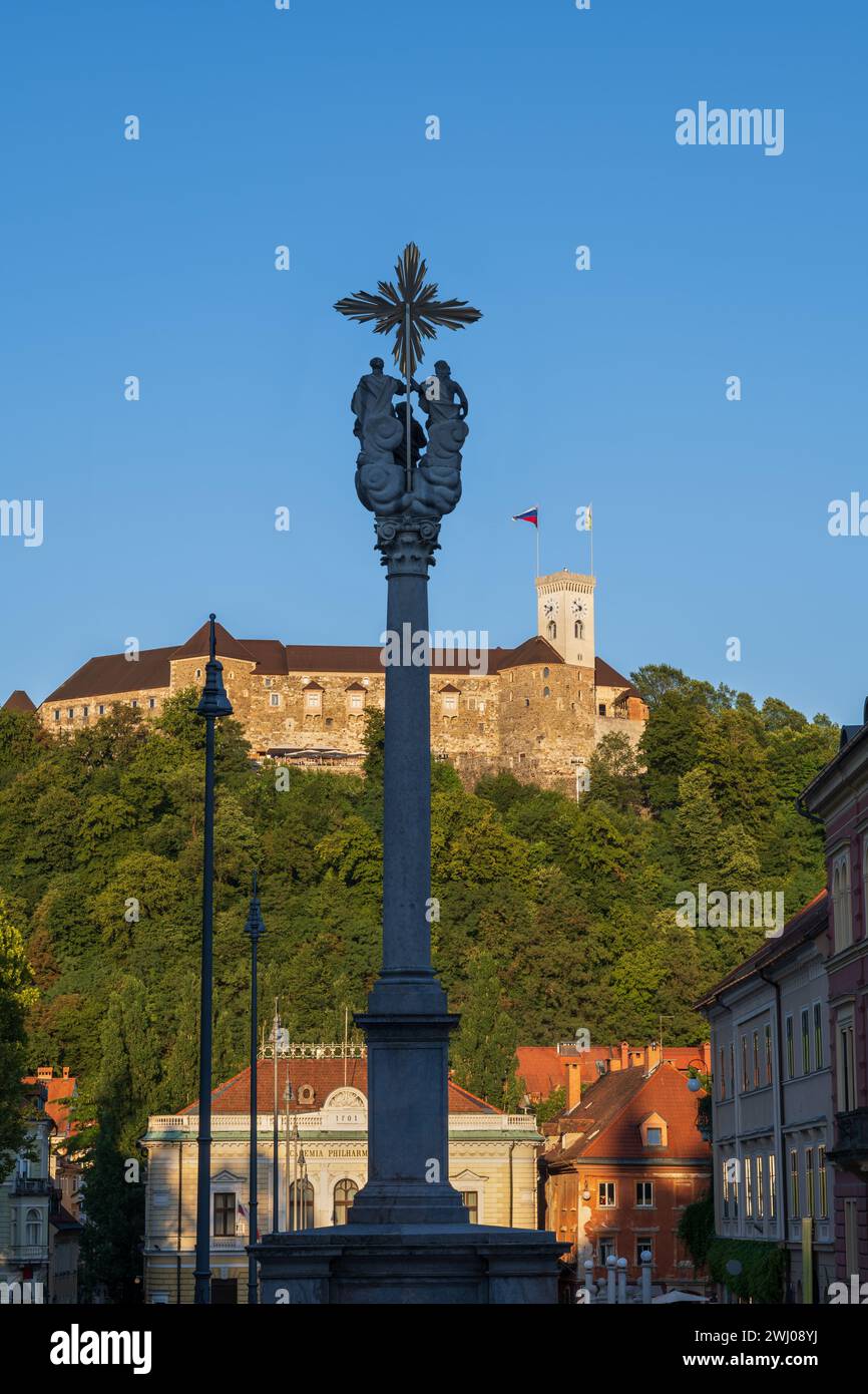 Die Dreifaltigkeitssäule, das Schloss von Ljubljana und das Gebäude der slowenischen Philharmonie bei Sonnenuntergang in der Stadt Ljubljana, Slowenien. Stockfoto