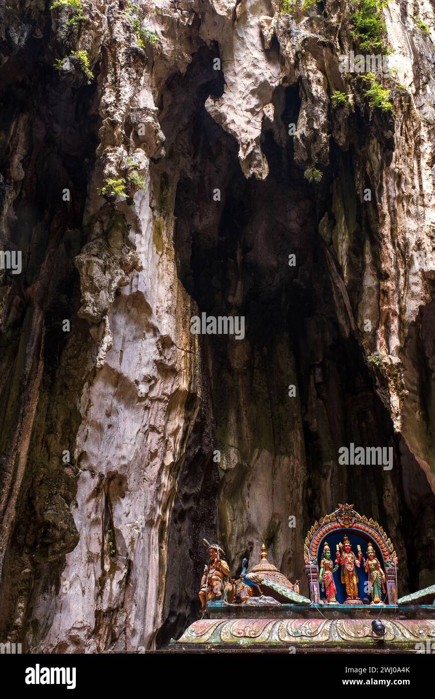 Exquisite Figuren hinduistischer Gottheiten auf dem Dach eines hinduistischen Tempels mit überhängenden Höhlenstalaktiten. Batu-Höhlen, Malaysia Stockfoto