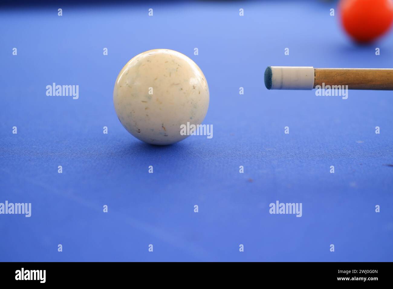 Billard-Kugeln und Billard-Queue sind an einem sonnigen Sommertag im Freien auf dem blauen Billard-Tisch. Queue auf dem Tisch, kurz vor dem Ball, Bokeh-Foto Stockfoto