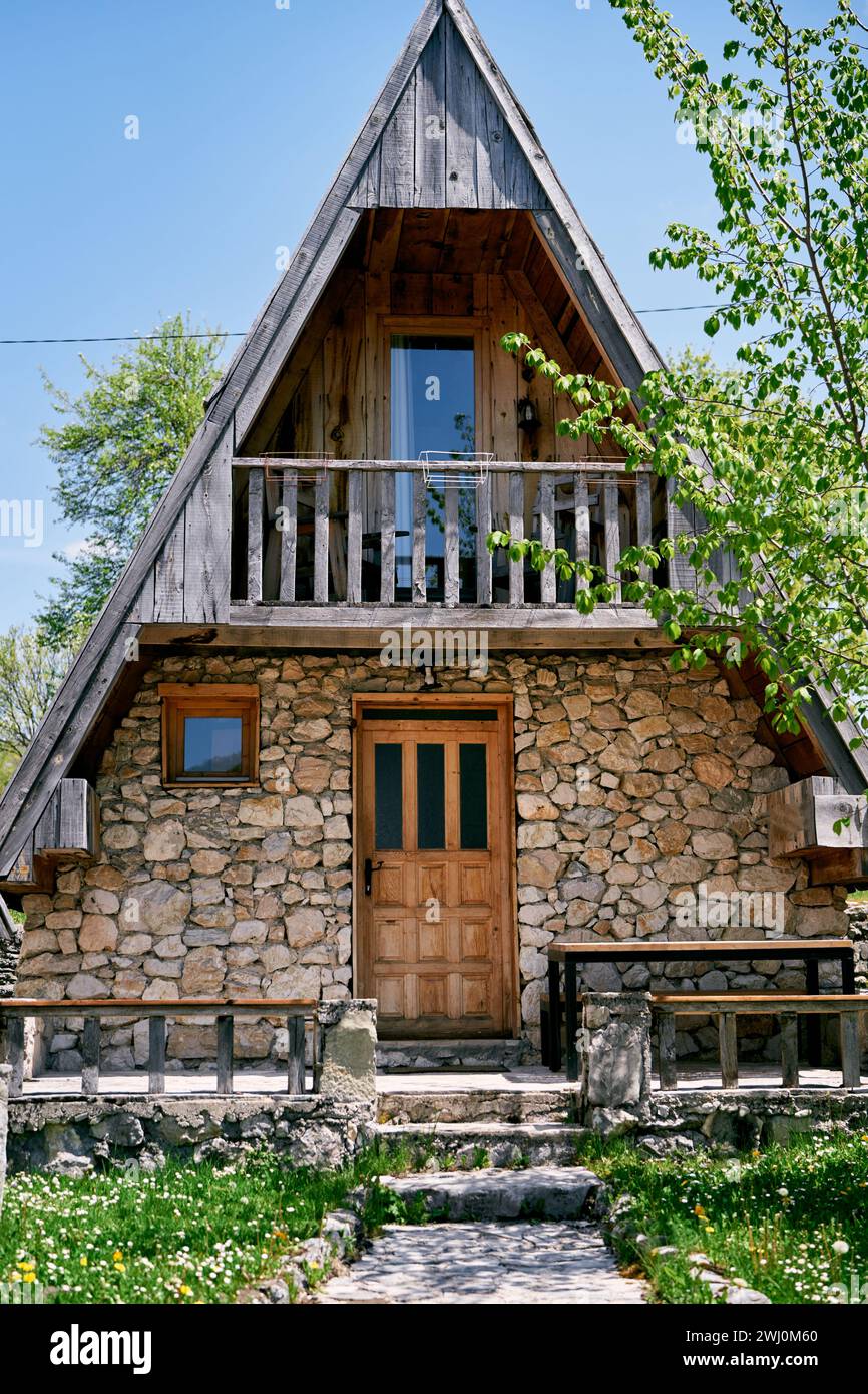 Gepflasterter Weg zu einem dreieckigen Steinhaus in einem grünen Garten Stockfoto