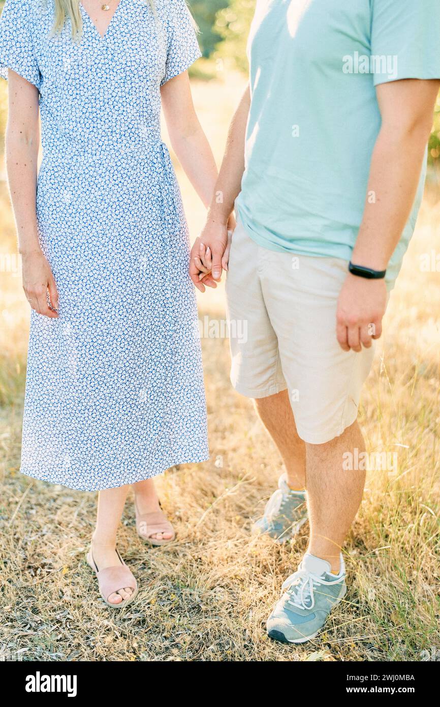 Mann und Mädchen stehen mit Händen auf trockenem Gras. Abgeschnitten. Gesichtslos Stockfoto