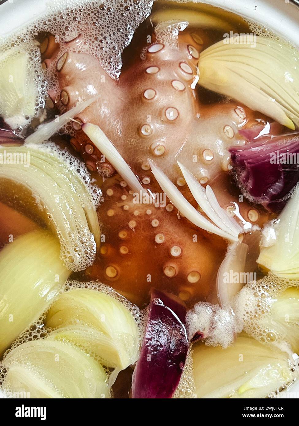 Oktopustentakel mit Zwiebelstücken kochen in einem Topf Stockfoto