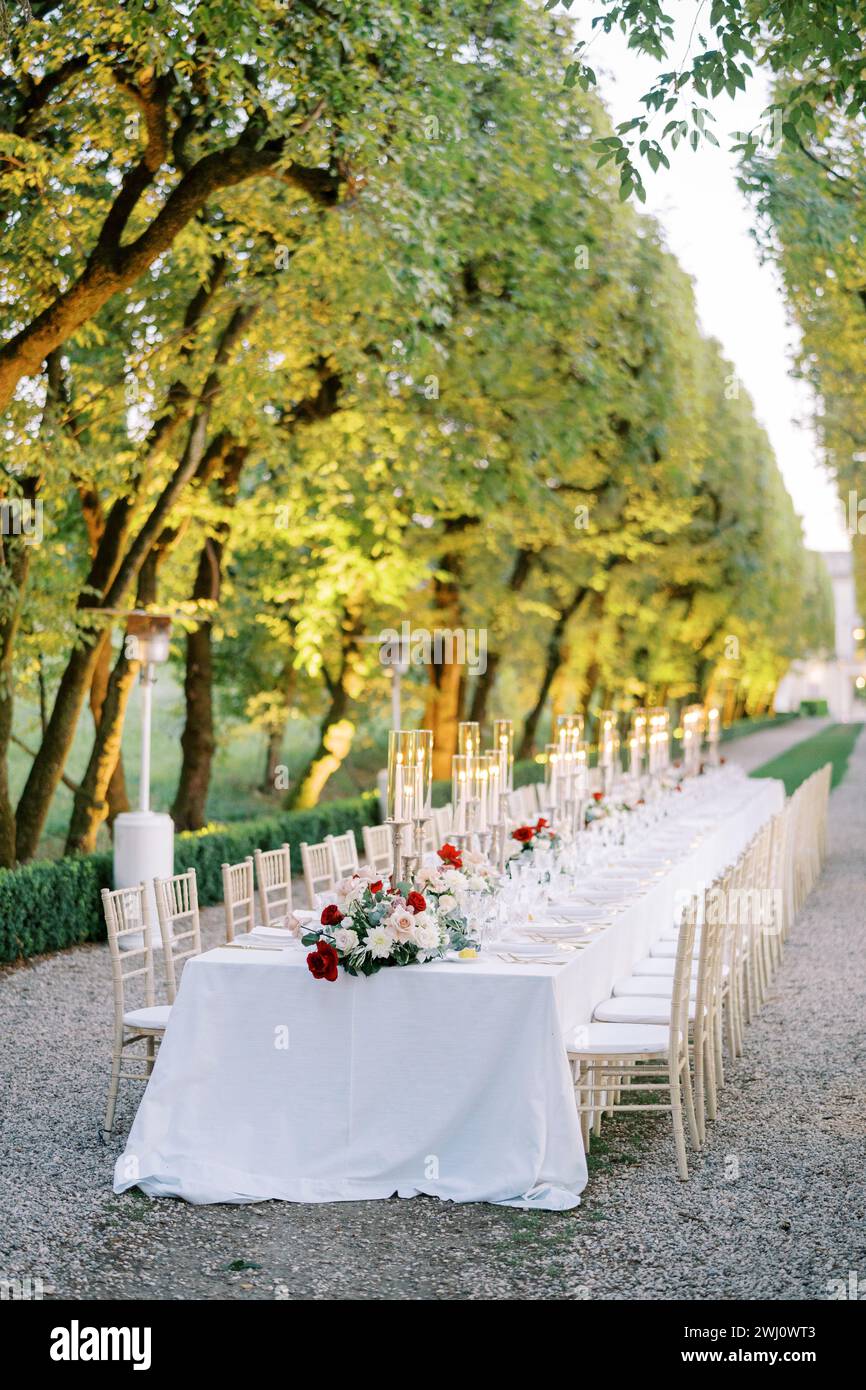 Gedeckter Tisch mit Blumensträußen und beleuchteten Kerzenständern im Park Stockfoto