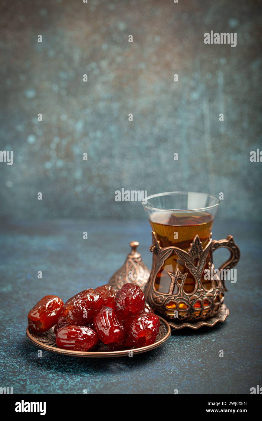 Das Fastenbrechen mit getrockneten Datteln während des Ramadan Kareem, Iftar-Mahlzeit mit Datteln und arabischem Tee in traditionellem Glas, Blick auf den Winkel Stockfoto