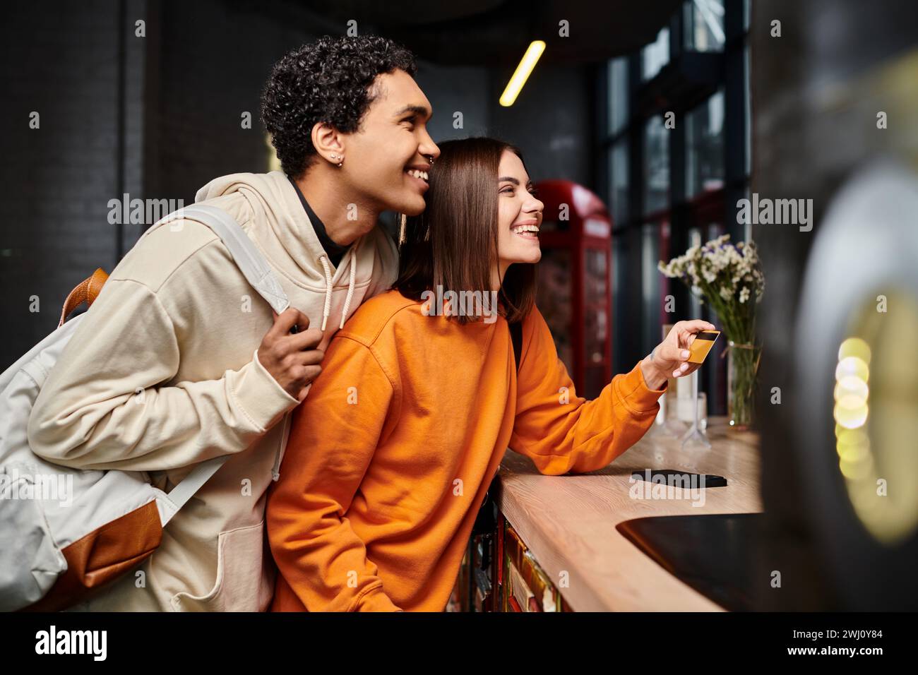 afroamerikanischer Mann und glückliche Frau mit Kreditkarte an der Rezeption im Hostel, Reise Stockfoto