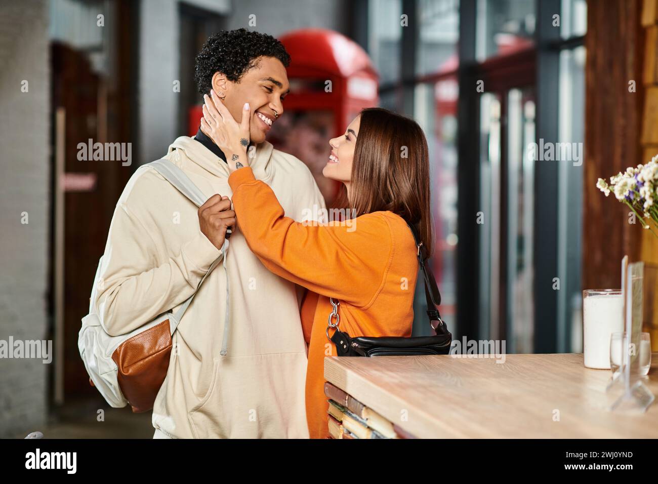 Ein liebevolles, vielseitiges Paar teilt einen zärtlichen Moment, während die Frau das Gesicht des Freundes berührt Stockfoto