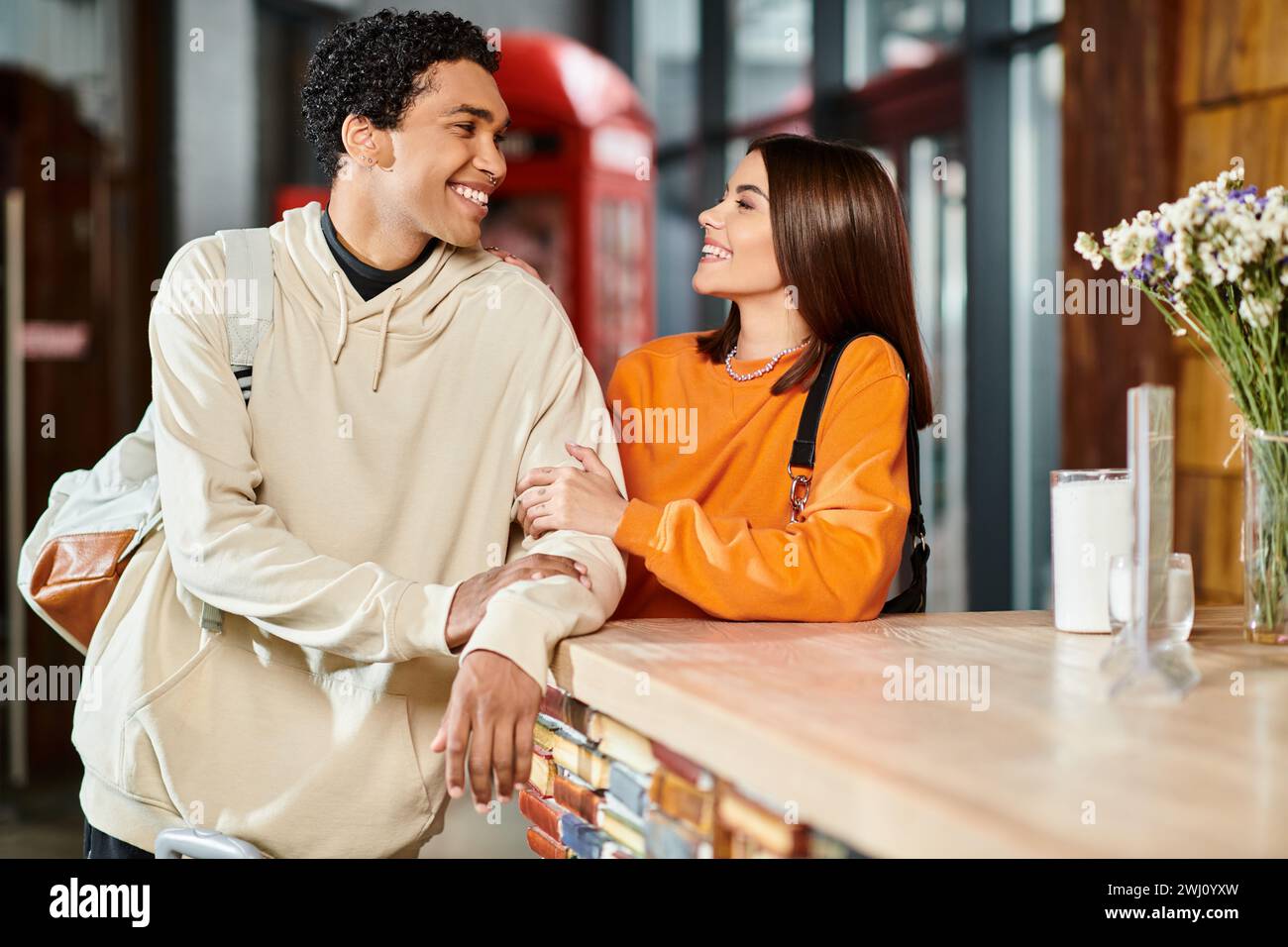 Glücklicher schwarzer Mann und eine Frau, die ein Gespräch genießen, während sie an der Rezeption im Hostel stehen Stockfoto