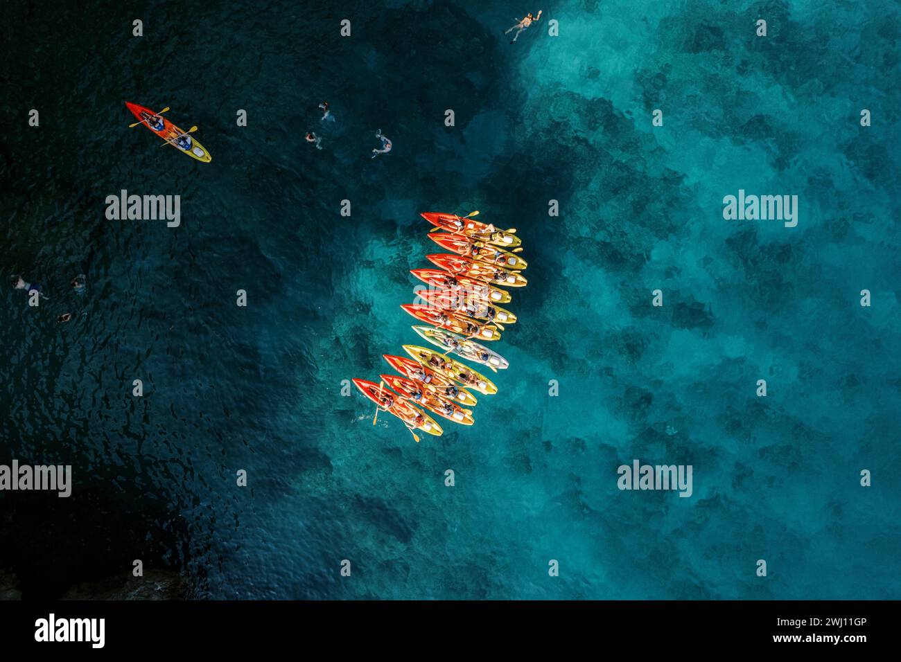 Das Captain Boot segelt in Richtung einer Reihe von Kajaks im tiefen türkisfarbenen Meer. Draufsicht Stockfoto
