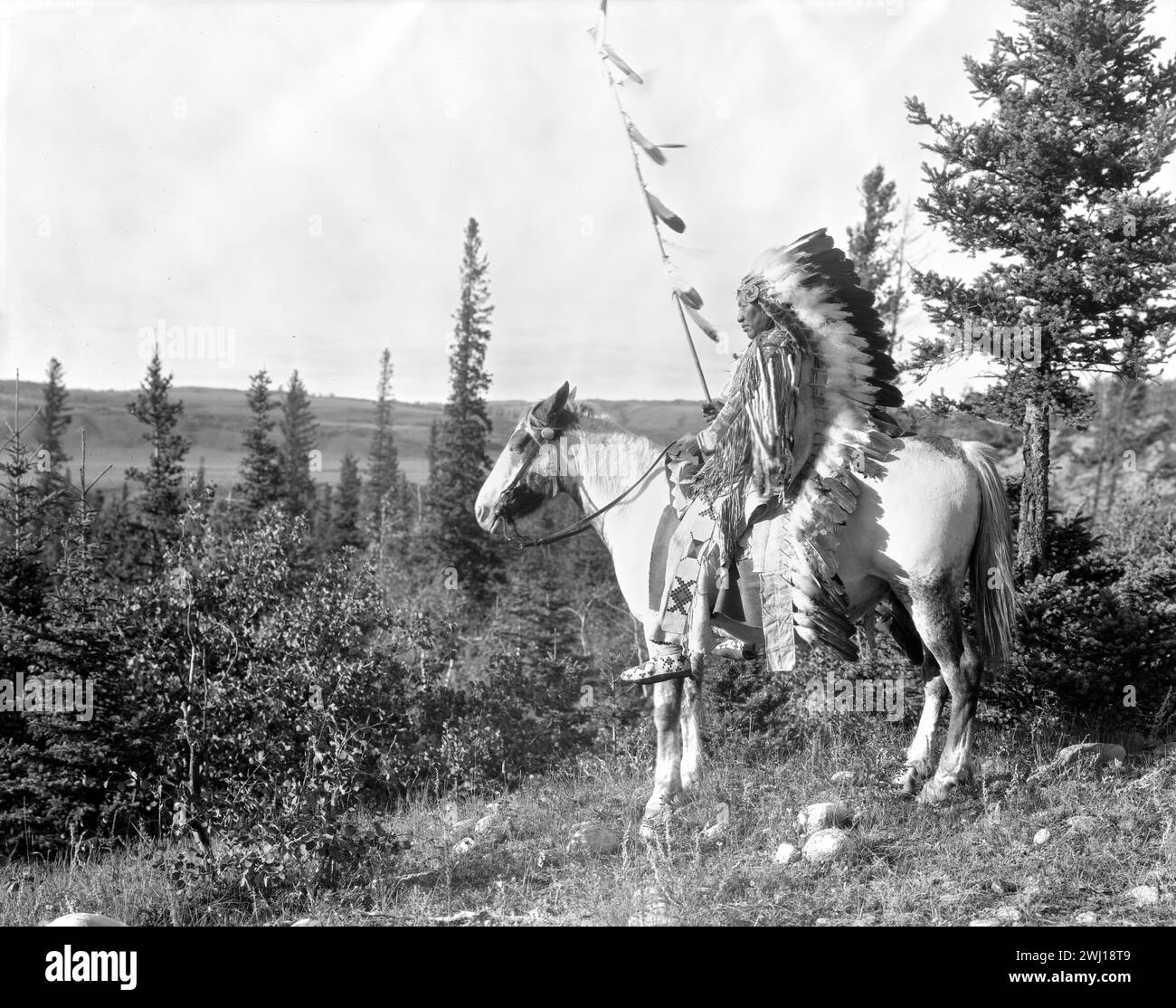 Vintage First Nation Bildporträt von Walking Buffalo, Anführer von Stoney-Nakoda, auf seinem Pferd in Trachtenkleidung um 1910 Stockfoto