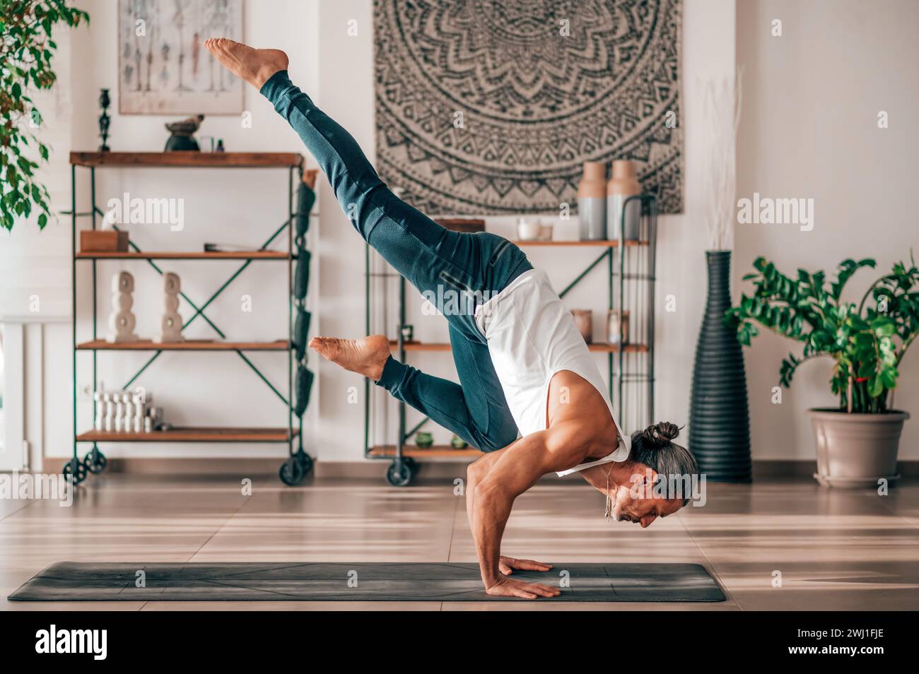 Flexibler Erwachsener, der Eka Pada Galavasana während des Fitness-Workouts zu Hause vorführt Stockfoto