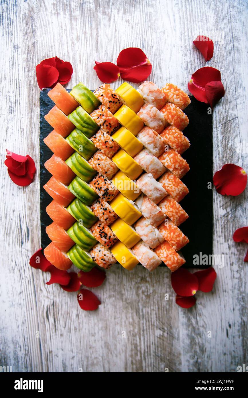 Verschiedene japanische Sushi-Rollen auf schwarzem Hintergrund. Asiatische oder japanische Küche Stockfoto