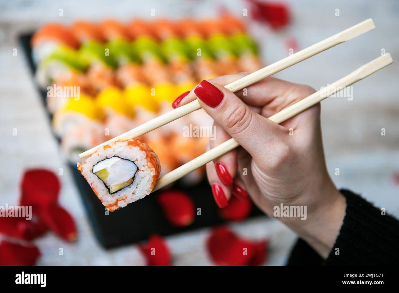 Verschiedene japanische Sushi-Rollen auf schwarzem Hintergrund. Asiatische oder japanische Küche Stockfoto
