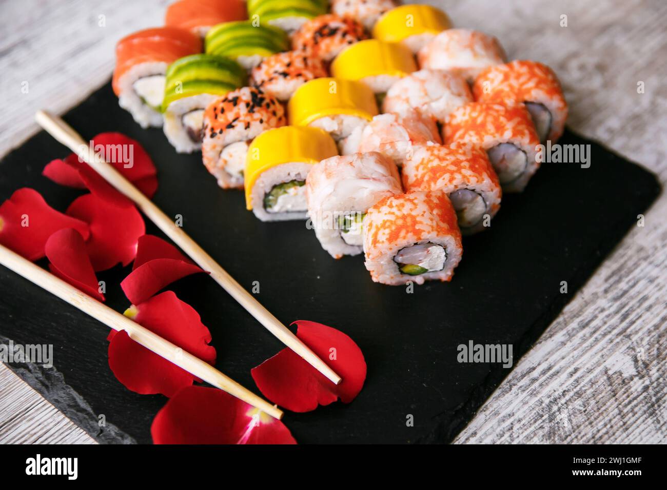 Verschiedene japanische Sushi-Rollen auf schwarzem Hintergrund. Asiatische oder japanische Küche Stockfoto