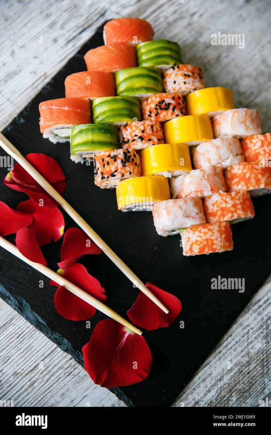 Verschiedene japanische Sushi-Rollen auf schwarzem Hintergrund. Asiatische oder japanische Küche Stockfoto