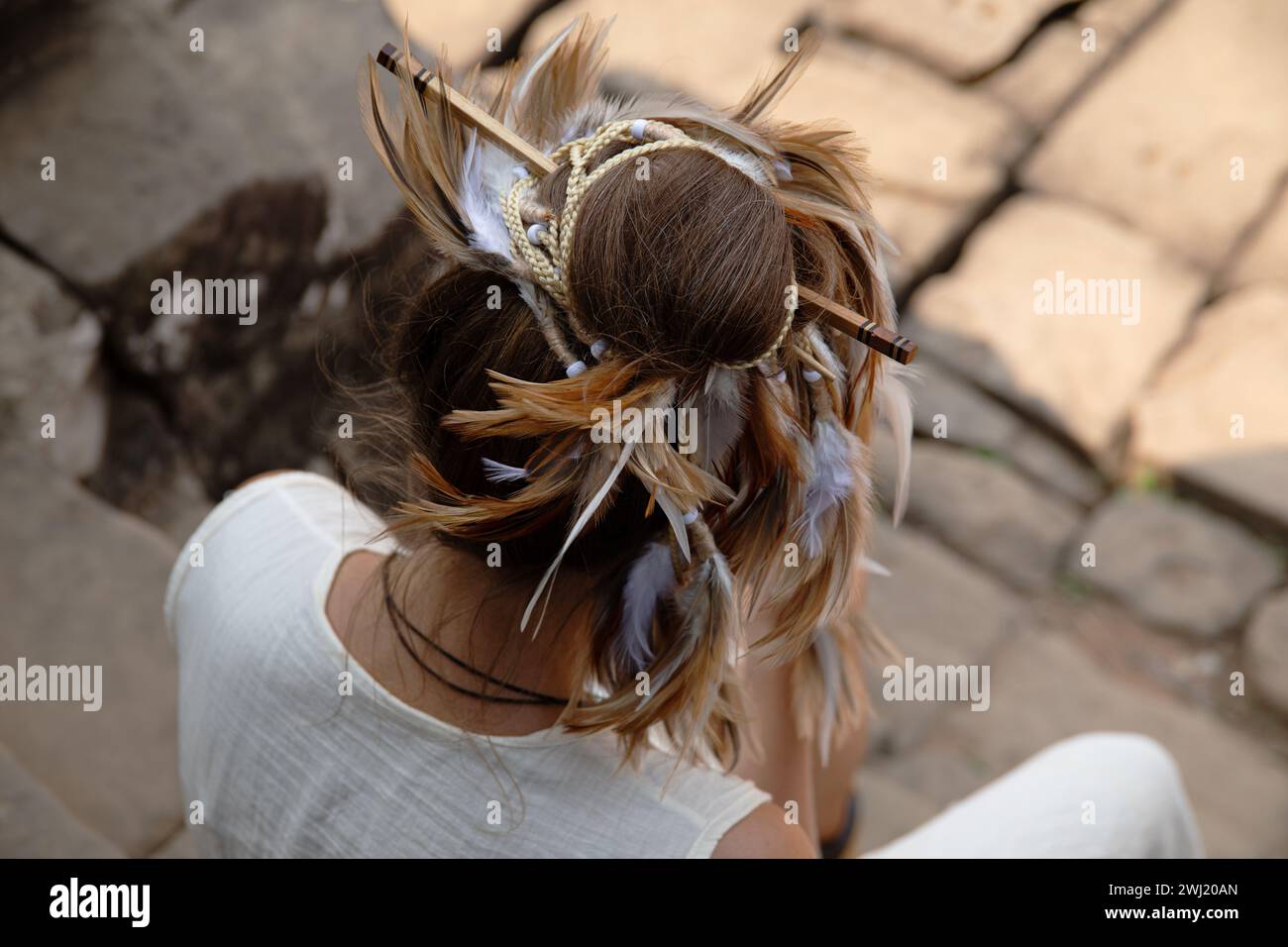 Stilvolle weibliche Frisur mit Federn, Zöpfen und Stäbchen Stockfoto