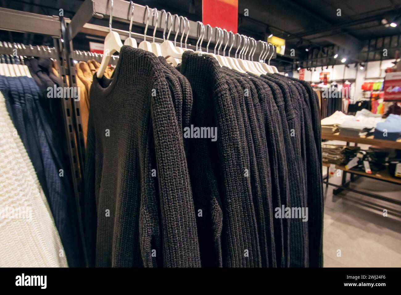 Schwarze Pullover an Kleiderbügeln in der Nähe des Ladens Stockfoto