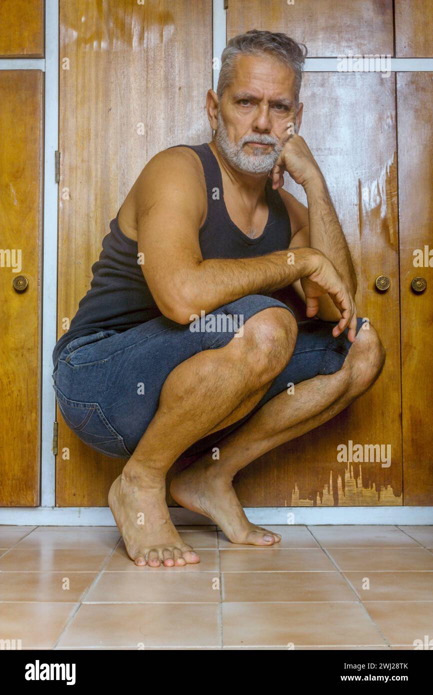 Senior-Mann mit grauem Haar und Flexibilität, der auf dem Boden sitzt Stockfoto